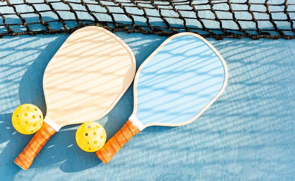 Two pickleball paddles laying on a court